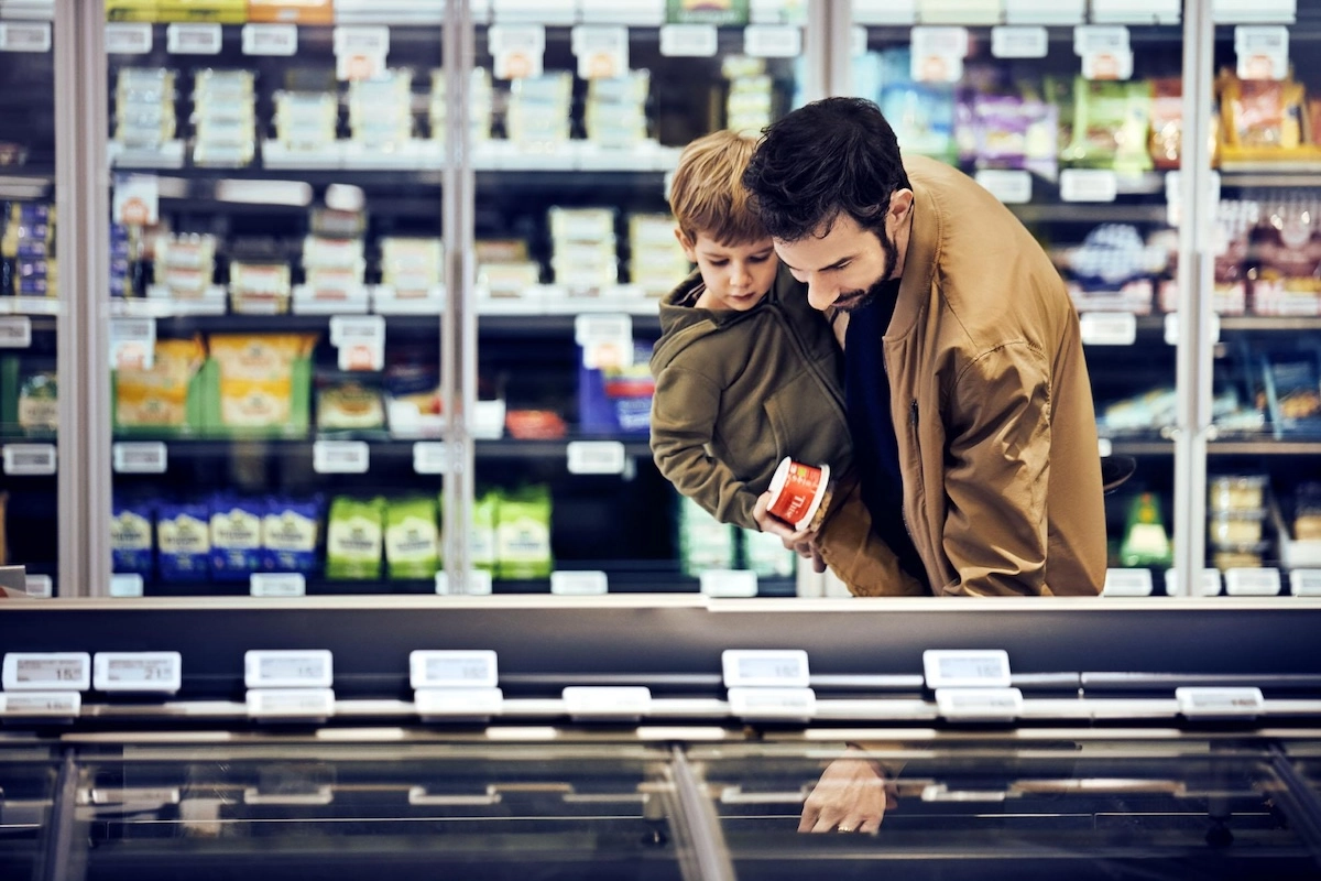 En familiefar bøjer sig ned efter en vare i supermarkedets køledisk. Han bør nu holde ekstra øje med prisskiltet. (Foto: Coop)